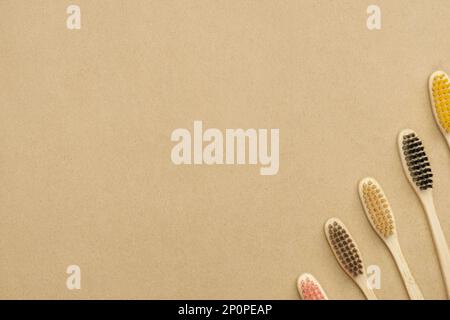 Multiple multicolor bamboo toothbrushes are lying on craft eco paper. Copy space, top view. Stock Photo