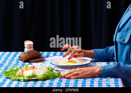 Female hand putting cigarette into egg yolk on fried eggs at checkered retro tablecloth over black background. Food pop art photography. Stock Photo