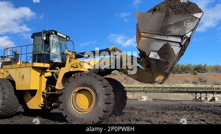Huge Wheel Loader Loading Coal On Trucks, Coal Mine. Stock Photo