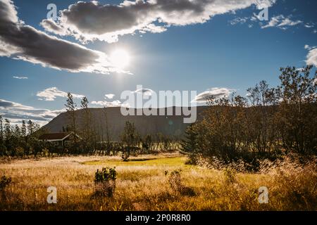 Icelandic dwelling with blue sky and fluffy white clouds over distant mountain range Stock Photo