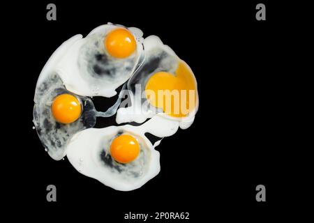 Preparing and frying four eggs in oil,  isolated on black background Stock Photo