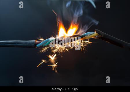 flame smoke and sparks on an electrical cable, fire hazard concept, soft focus close up Stock Photo