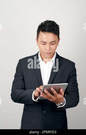 Portrait young asian business man in suit standing using tablet computer to internet isolated on white background Stock Photo