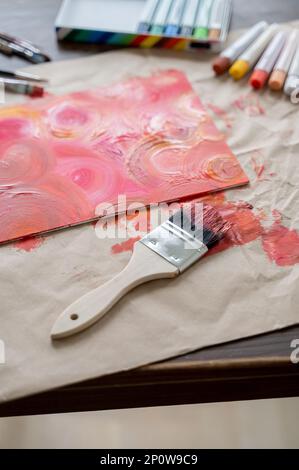 Painted Canvas with brushes and paint on wooden table Stock Photo