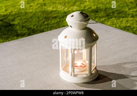 Lit lantern on a table in the garden at night. Stock Photo