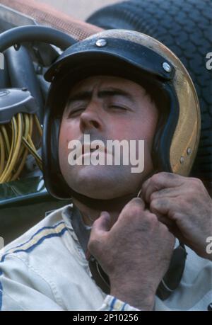 Australian driver Jack Brabham, 3 times Formula 1 world champion (1959, '60 & '66), tying helmet.preparing for start at Belgian Grand Prix at Spa Fr Stock Photo