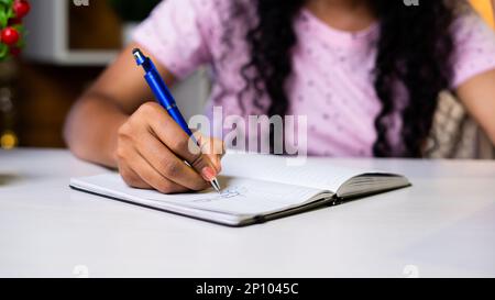 close up shot of girl hands writing or making notes on study desk at home. Stock Photo