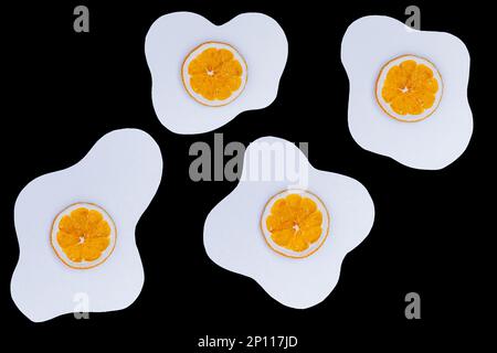 Creative layout made of scrambled eggs with circles of dried orange instead of yolk on a black background. Stock Photo