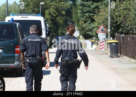 Police officers walk along a road in Reuden, Germany,Thursday Aug. 25, 2016. Three people have been wounded in an armed standoff between police and members of a group that denies the legitimacy of the modern German state in Reuden, eastern Germany. A spokeswoman for police in the eastern state of Saxony-Anhalt says the shootout happened while about 100 police, including a tactical response team, were trying to enforce an eviction order against a 41-year-old “Reich citizen” early Thursday. (Sebastian Willnow/dpa via AP)