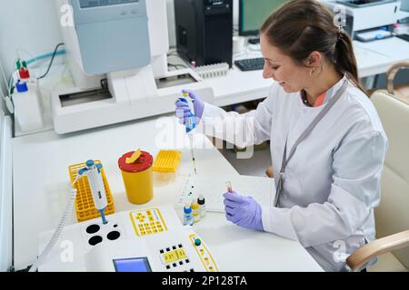 Female laboratory assistant conducts blood group test in testing unit Stock Photo