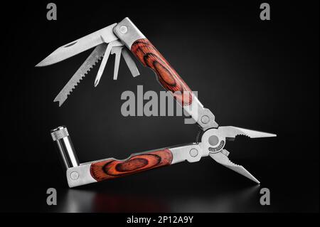 Pocket multi tool knife packed with accessories, fully opened on black gradient background. Stock Photo
