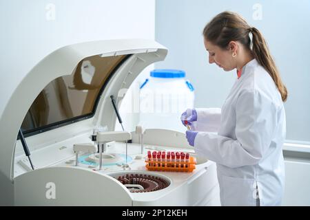 Woman scientist conducts laboratory diagnostics in a modern biochemical analyzer Stock Photo
