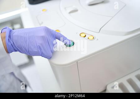 Laboratory assistant presses the button on immunochemiluminescent analyzer Stock Photo
