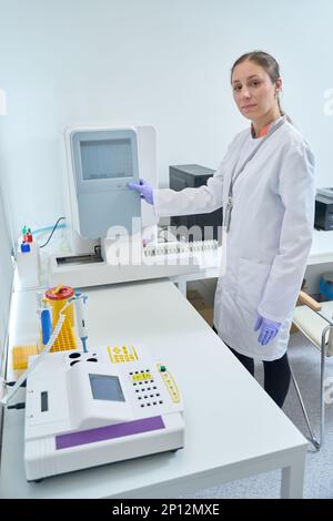 Health worker turns on the hematology analyzer Stock Photo