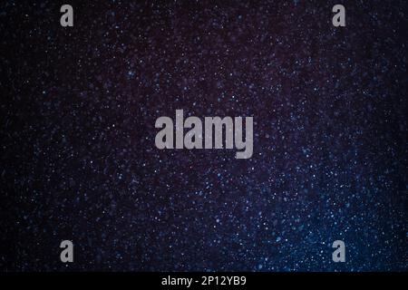 Organic dust particles floating on a colorful light beam on black background. Stock Photo