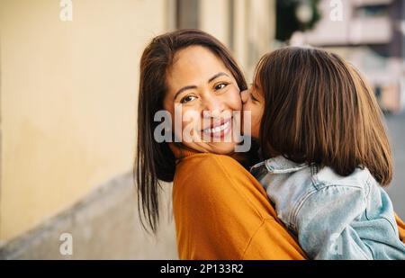 Happy filipina mother with her daughter having tender moments in the city center - Lovely family outdoor Stock Photo