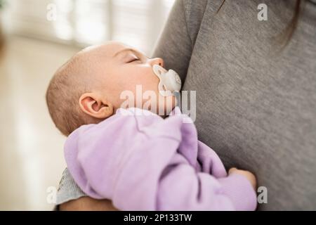 Closeup portrait of a newborn baby sleeping in mother's arms - Motherhood concept Stock Photo