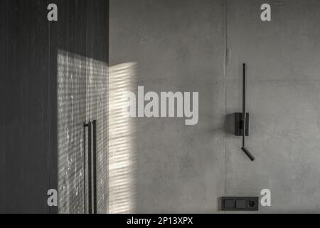 Minimalistic black wall light in modern interior in grey and black colours, concrete wall design, clay wall. Contemporary interior design aesthetics w Stock Photo