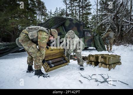 Army Sgt. Meranda Leisgana and Sgt. Trayton Pankratz, 1-120th Field Artillery Regiment, opens a wooden crate of 105mm High Explosive shells for the M119 howitzer during Northern Strike 23-1, Jan. 25, 2023, at Camp Grayling, Mich. Units that participate in Northern Strike’s winter iteration build readiness by conducting joint, cold-weather training designed to meet objectives of the Department of Defense’s Arctic Strategy. Stock Photo