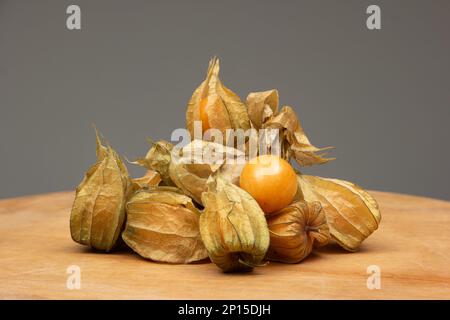 Pile of ripe physalis fruits on a wooden table. Close up studio shot, front view. Stock Photo