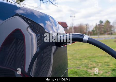 Plug of the charging cable plugged into an electric car Stock Photo