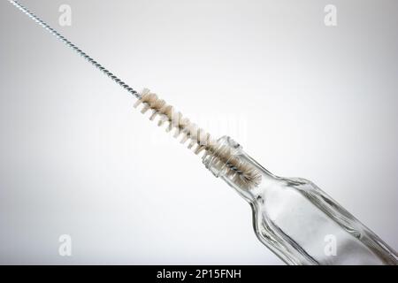 Thin wire brush for cleaning bottles. Inside small empty glass bottle. Close up studio shot, isolated on white background. Stock Photo