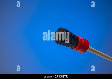 Dusting brush with wooden handle. Close up studio shot, isolated on blue background. Stock Photo