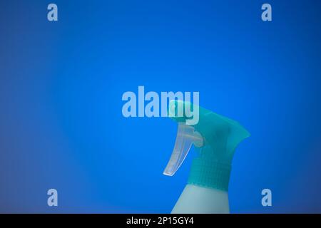 Light blue water sprayer bottle nozzle. Close up studio shot isolated on a blue background. Stock Photo