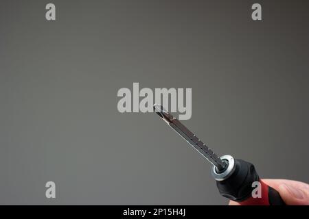 Turn screwdriver in man's hand. Close up studio shot, isolated on gray background. Stock Photo