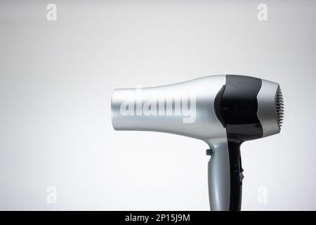 Generic silver hair dryer. Close up studio shot, isolated on blue background. Stock Photo