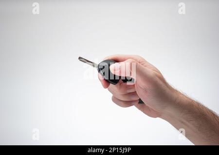 Generic plastic black car key fob held by Caucasian male hand. Close up studio shot, isolated on white background Stock Photo