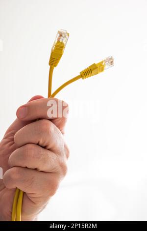 Caucasian male hand holding yellow Ethernet cable connectors close up shot isolated on white macro. Stock Photo
