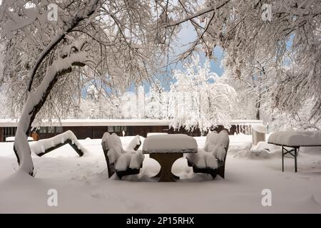 Snowy playground in the forest with snow covered picnic table and benches Switzerland. Stock Photo