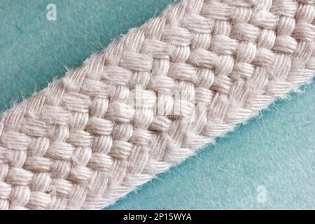 White woven shoelace extreme macro on blue background top view. Stock Photo