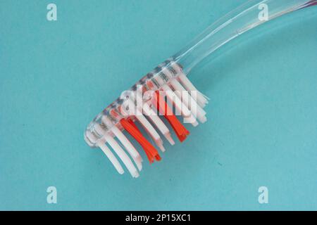Used tooth brush head with red a white brush isolated on blue background top view macro shot. Stock Photo