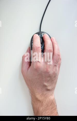 Male hand holding a computer mouse isolated on white top view. Stock Photo