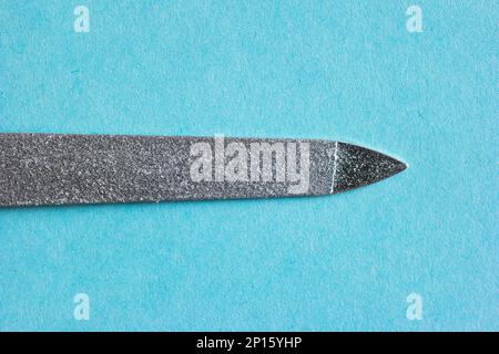Personal metal nail file macro close up shot isolated on blue background top view. Stock Photo