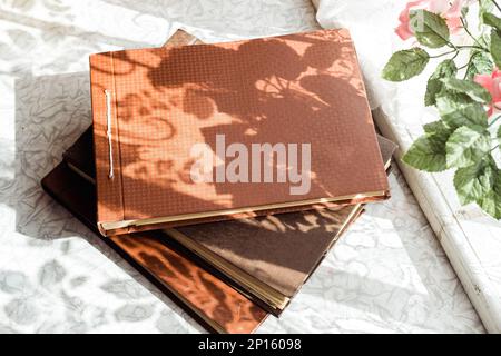 old brown photo albums are stacked on the table by the window, top view Stock Photo