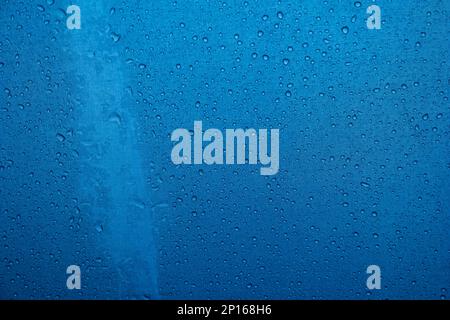 Rain water droplets accumulated on the surface of blue fabric umbrella close up detail shot. Stock Photo