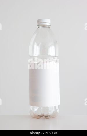 Clear empty plastic bottle with red lid and white empty label isolated on white vertical shot. Stock Photo