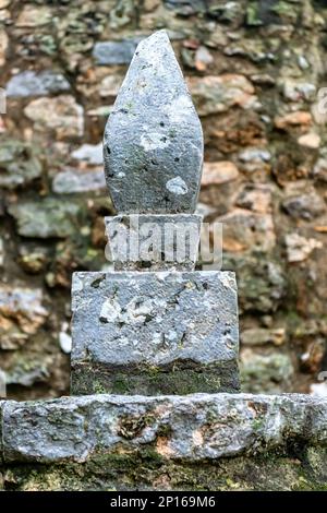 A decorative polished stone shape contrasts with a rustic wall in the background Stock Photo