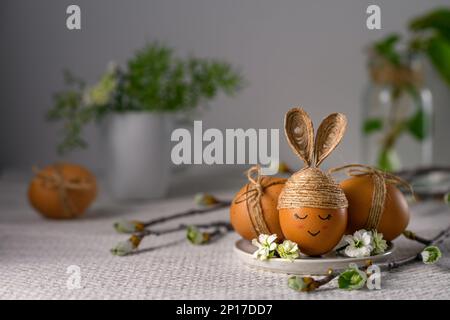 Easter bunny egg. Egg decorated with twine like a rabbit on white background. Handmade toy. Stock Photo