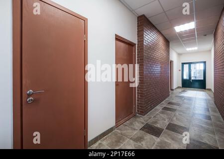 white empty long corridor with red brick walls in interior of modern apartments, office or clinic. Stock Photo