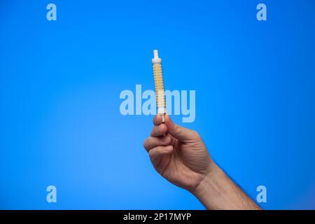 Multi LED long cylindrical replacement light bulb held by Caucasian male hand studio shot isolated of blue background. Stock Photo