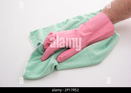 Pink latex cleaning glove on Caucasian male hand holding a light green microfiber cloth making cleaning gesture isolated on white background. Stock Photo