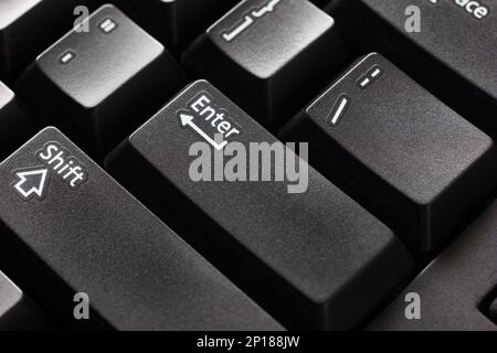 Black plastic standard English computer keyboard close up macro shot top side view Enter button. Stock Photo