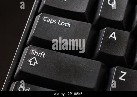 Black plastic standard English computer keyboard close up macro shot top side view Shift and Caps Lock buttons. Stock Photo