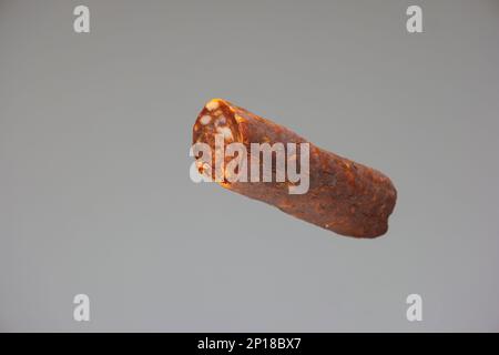 Home made Hungarian style smoked spicy salami close up studio shot isolated on gray background. Stock Photo