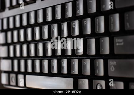 Black plastic standard English computer keyboard close up macro shot top side view. Stock Photo