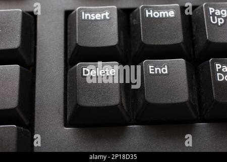 Black plastic standard English computer keyboard close up macro shot top side view delete button. Stock Photo